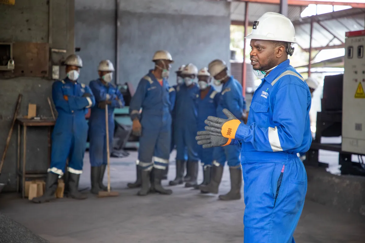Instructor briefing workers wearing protective equipment in a factory