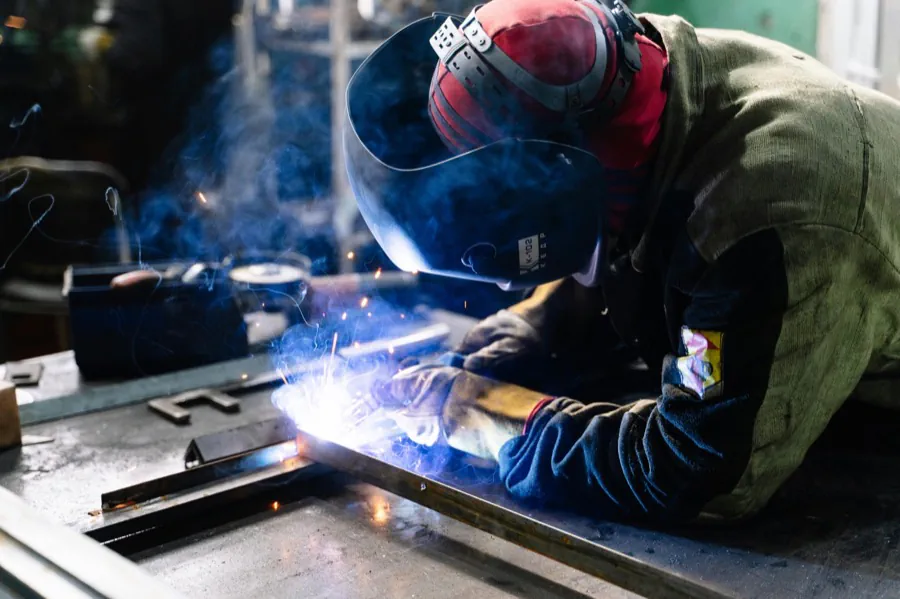 Welder joining steel in a fabrication shop